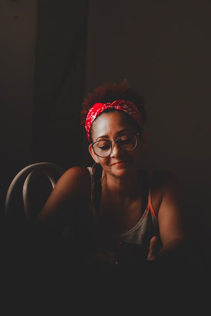 Woman in a calming, seated yoga pose with her eyes closed, room bathed in soft evening light.